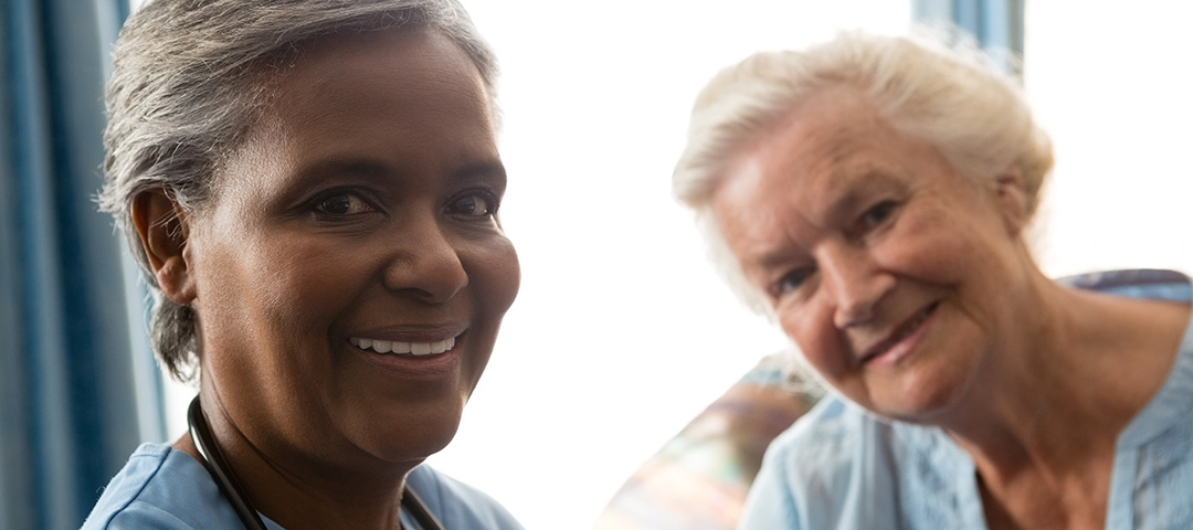 a health coach on the left smiling at the camera with her patient smiling at the camera on the left